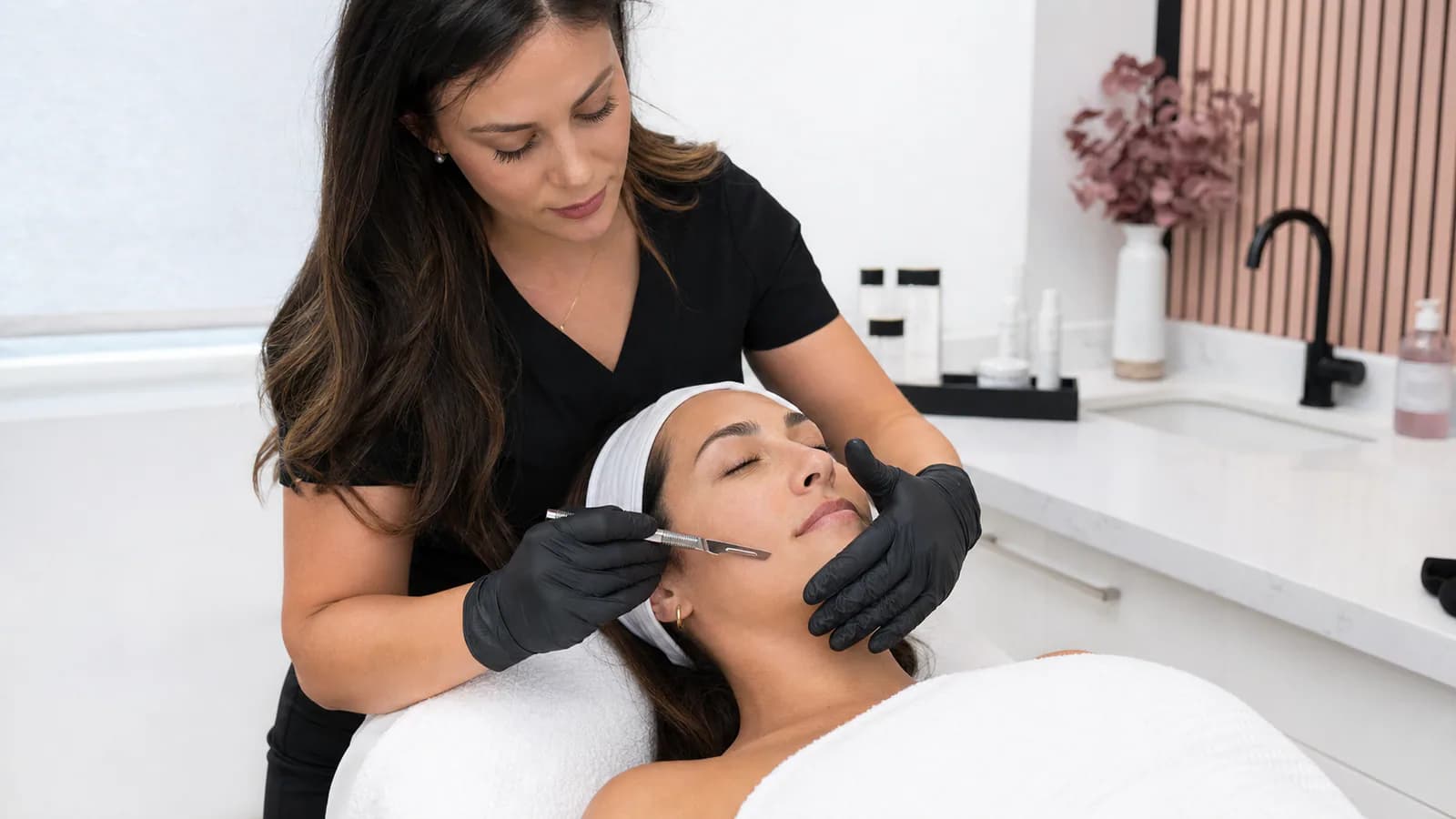 Esthetician performing a precise dermaplane facial treatment.